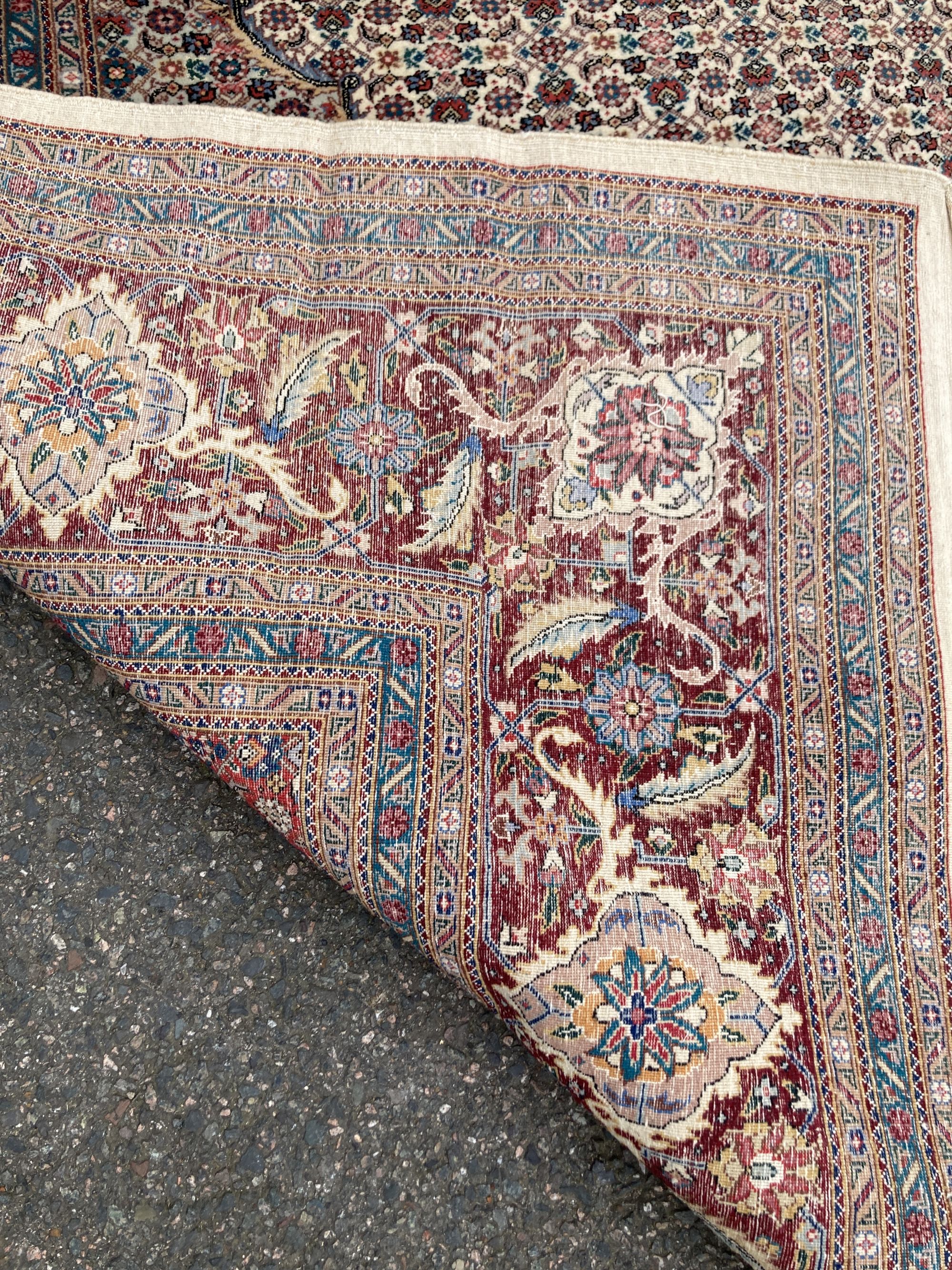 A Chinese Tabriz style carpet having burgundy central medallion on a foliate ivory ground, and a small Turkish rug